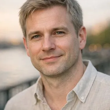 Man in his early forties, ash blonde hair, gray-green eyes, relaxed open collar